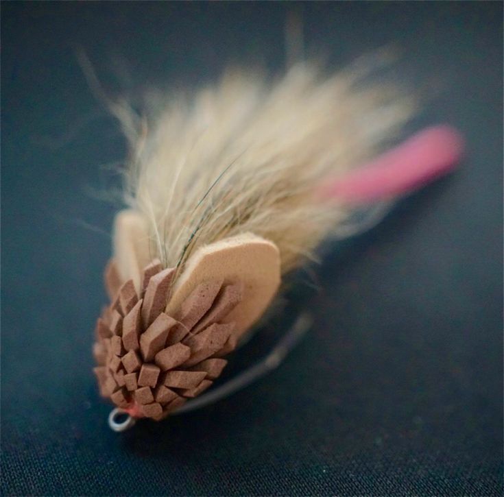 a feathered object with a pink handle on a black surface