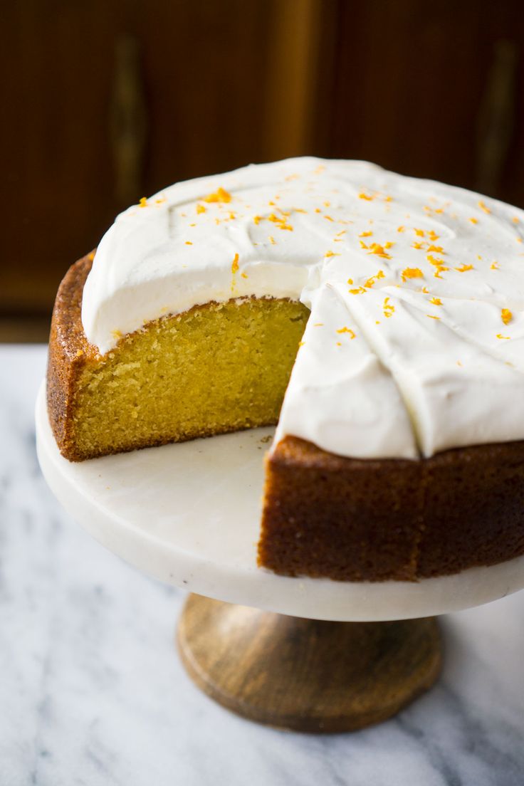 a cake with white frosting and orange sprinkles sits on a pedestal