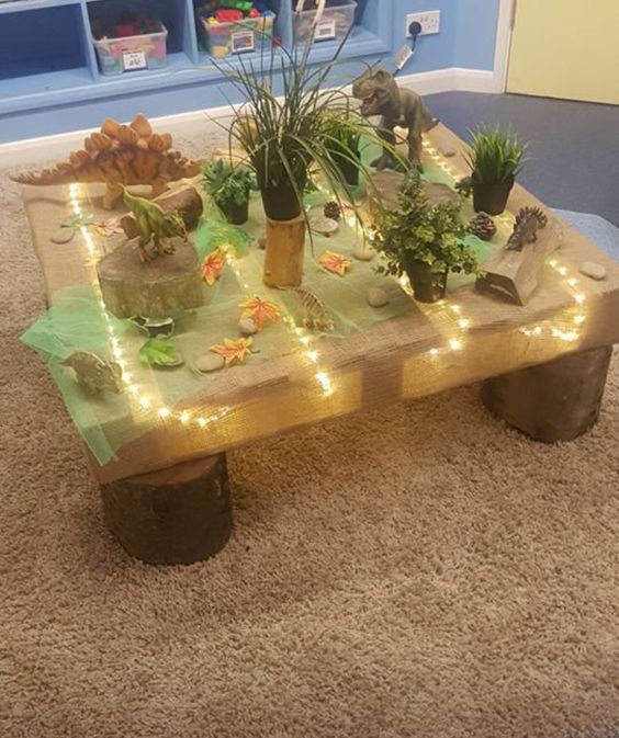 a table with plants and rocks on it in the middle of a carpeted room