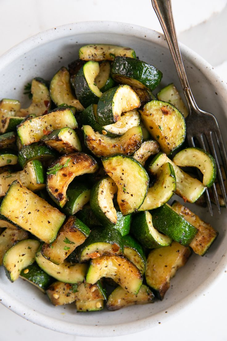 zucchini in a white bowl with a fork and text overlay that reads perfect sauteed zucchini