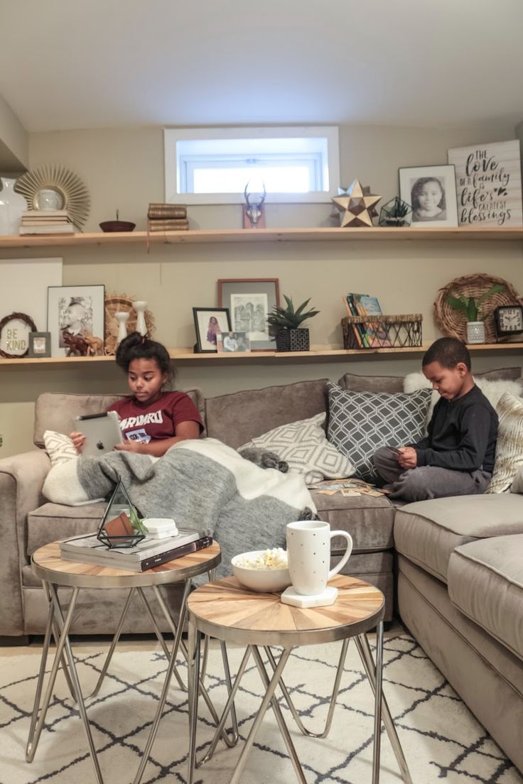 two people sitting on a couch in a living room next to a coffee table and sofa