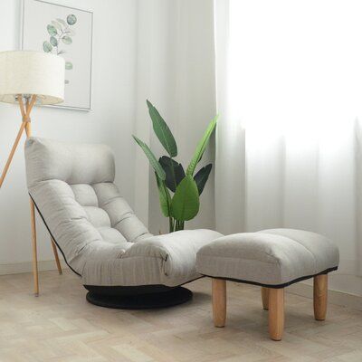 a chair and ottoman in a room with a potted plant on the floor next to it