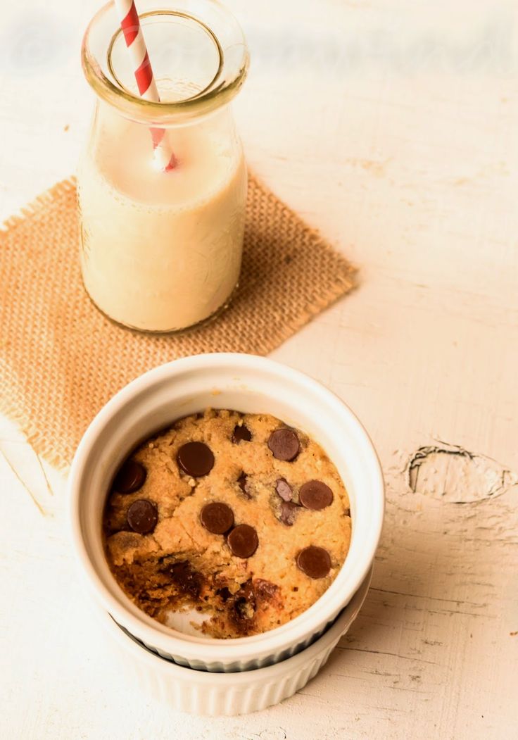 a cookie in a bowl next to a glass of milk