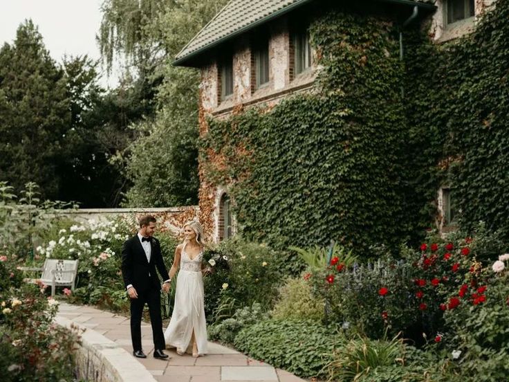 a bride and groom walking through the garden