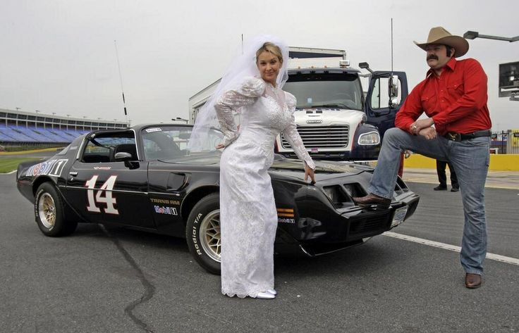 a bride and groom standing next to a race car