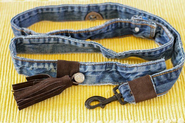 a pair of blue jeans with tassels on them sitting on top of a yellow blanket