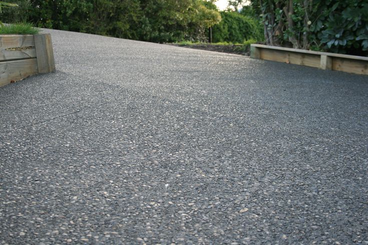 a skateboard is sitting on the edge of a paved road with trees in the background