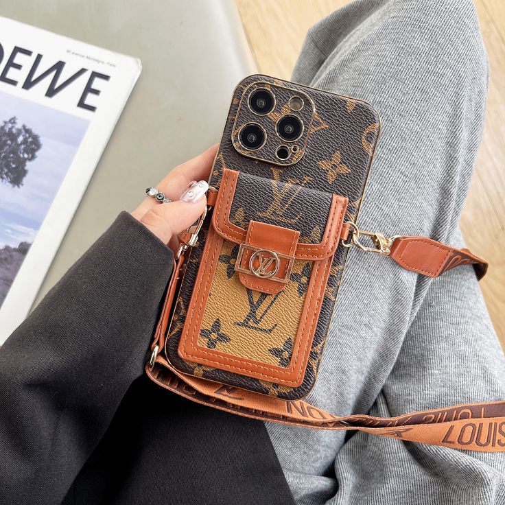 a person holding a cell phone case in their hand with a magazine on the table behind them