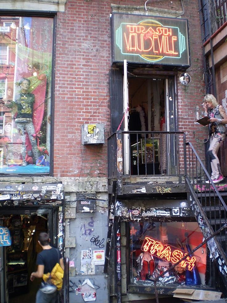 a man is walking down the street in front of a building with graffiti on it