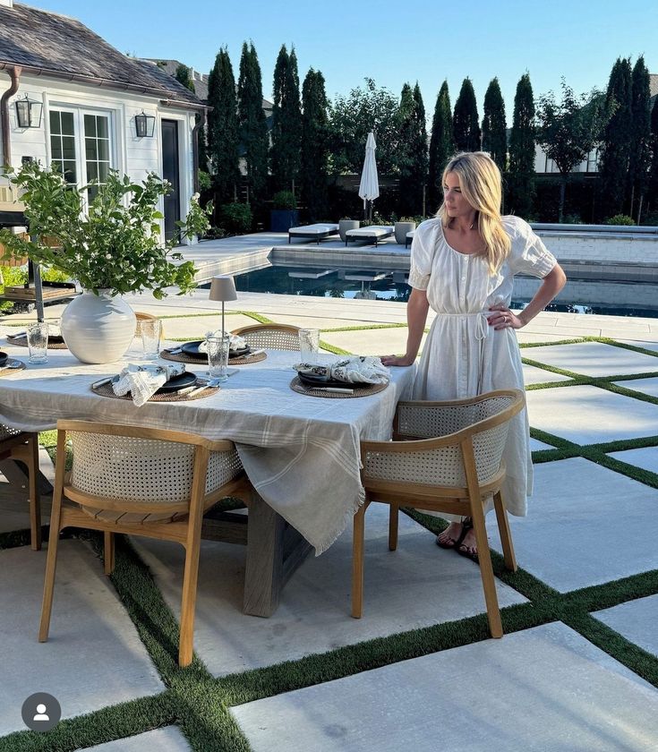 a woman standing next to a table with food on it in front of a pool