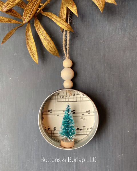 an ornament with a christmas tree on it and music notes hanging from the top