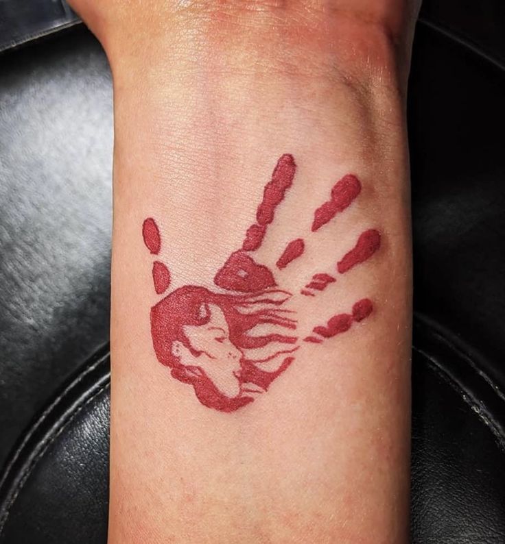 a woman's hand with red ink on her wrist