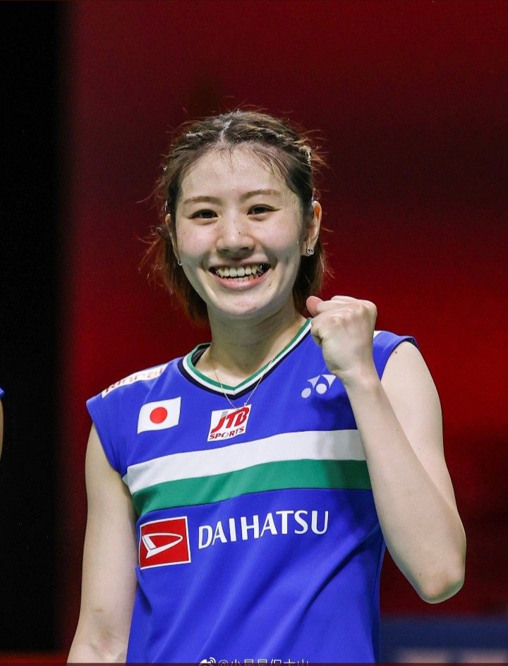 a woman holding a tennis racquet in her right hand and smiling at the camera