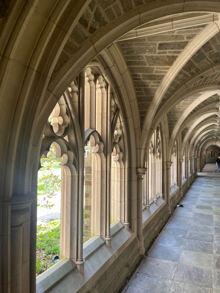 an arched hallway with stone flooring and arches on both sides, leading into the distance