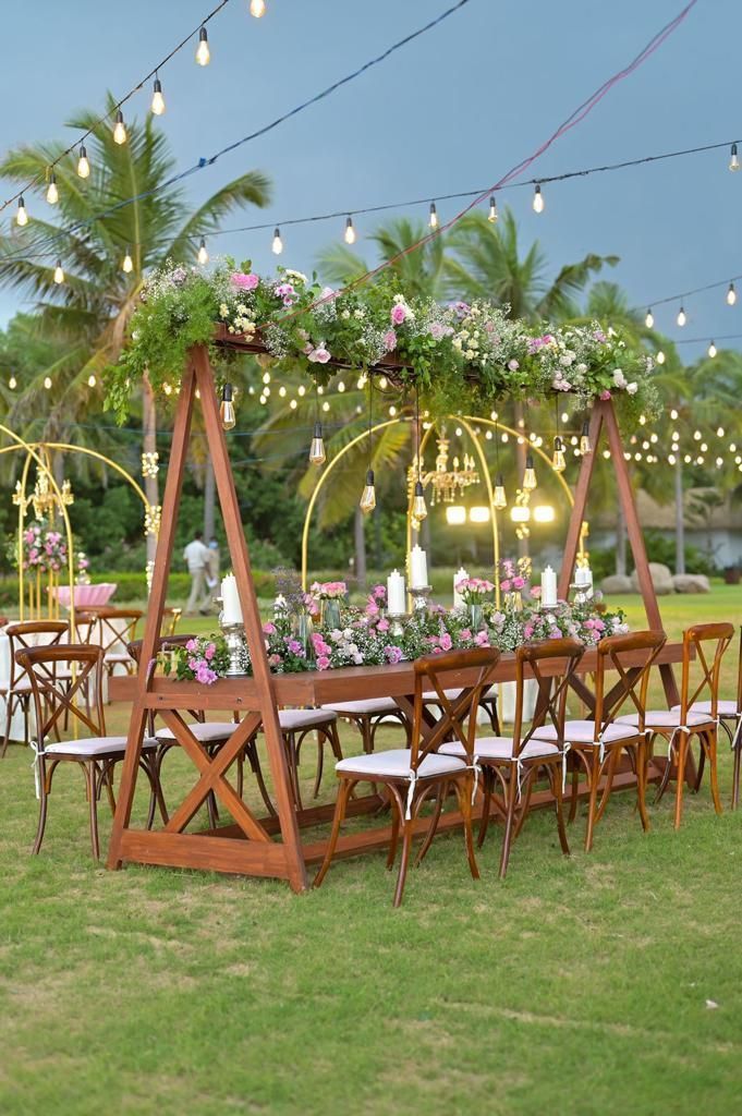 a long table with chairs and flowers on it in the middle of an open field