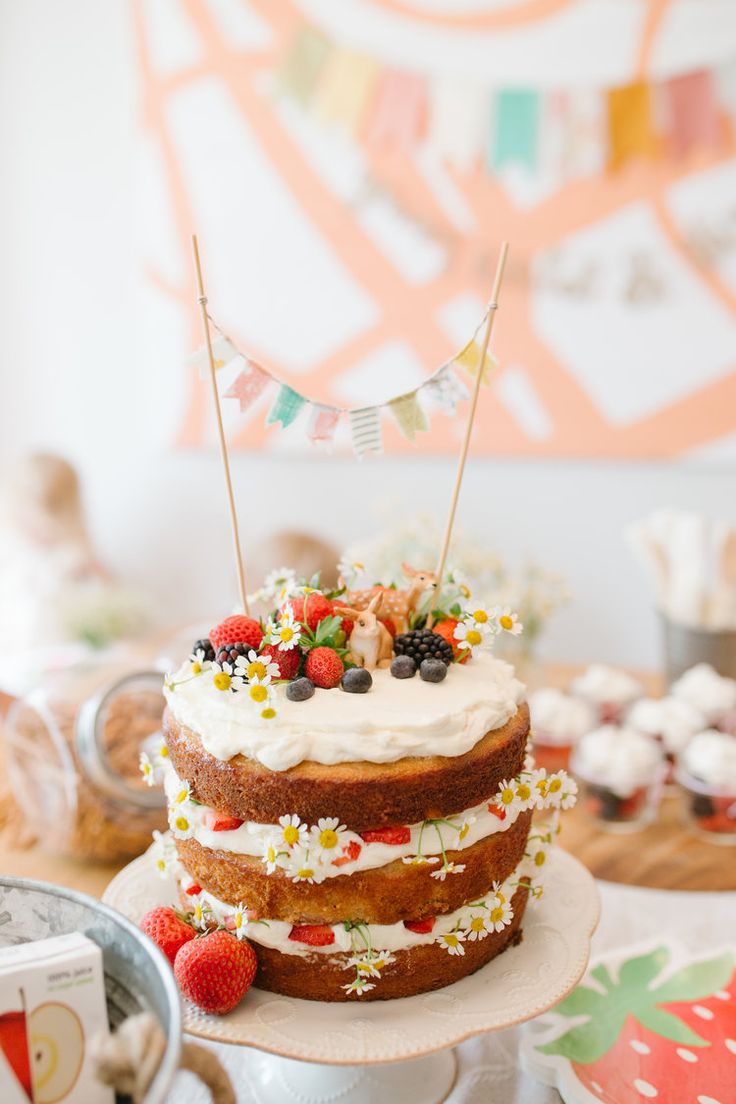 a cake sitting on top of a white plate topped with berries and strawberries next to a flag