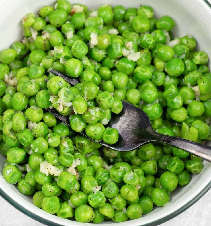 a bowl filled with green peas and a spoon