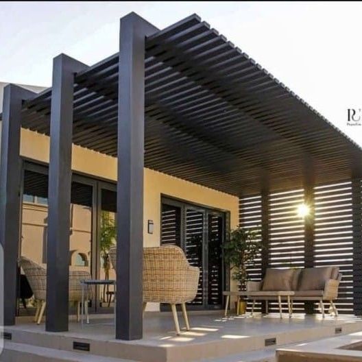 an outdoor covered patio area with furniture and sun shining through the slatted roof