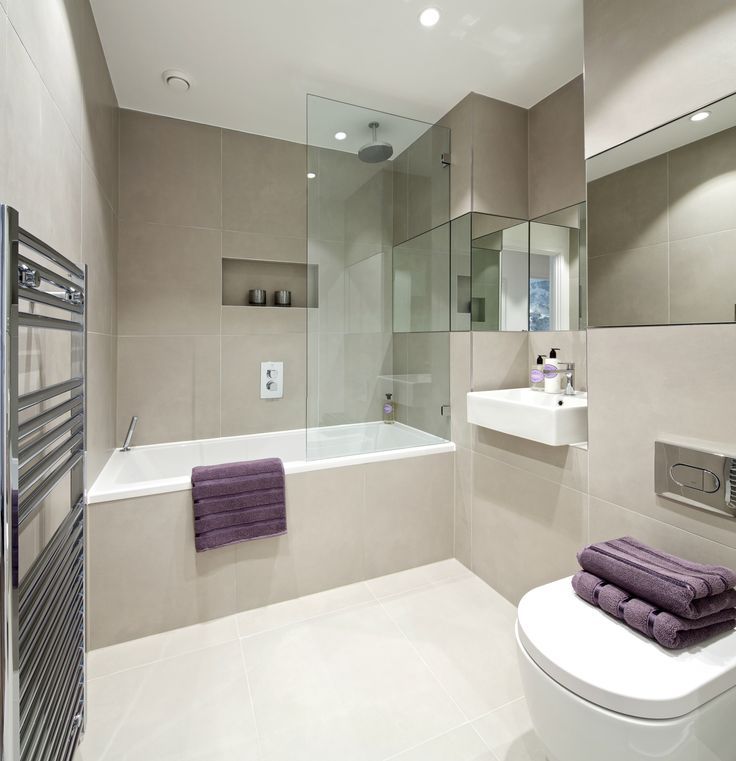 a white toilet sitting in a bathroom next to a bath tub under a mirror and towel rack