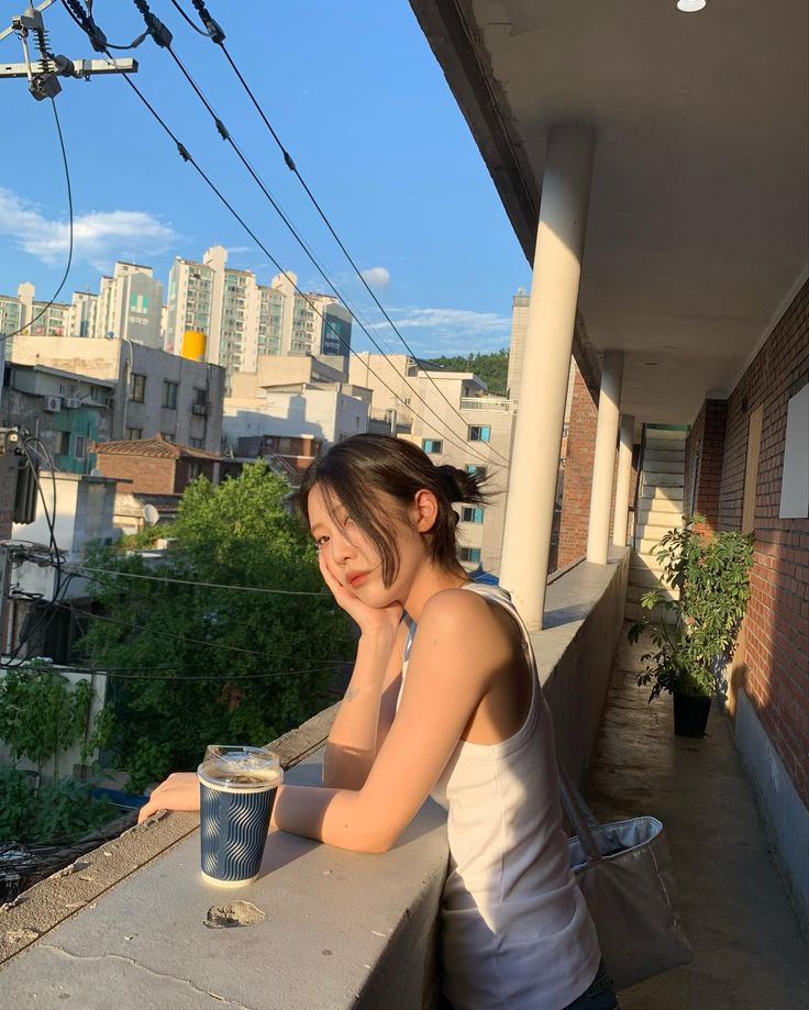 a woman sitting on a balcony with a cup of coffee