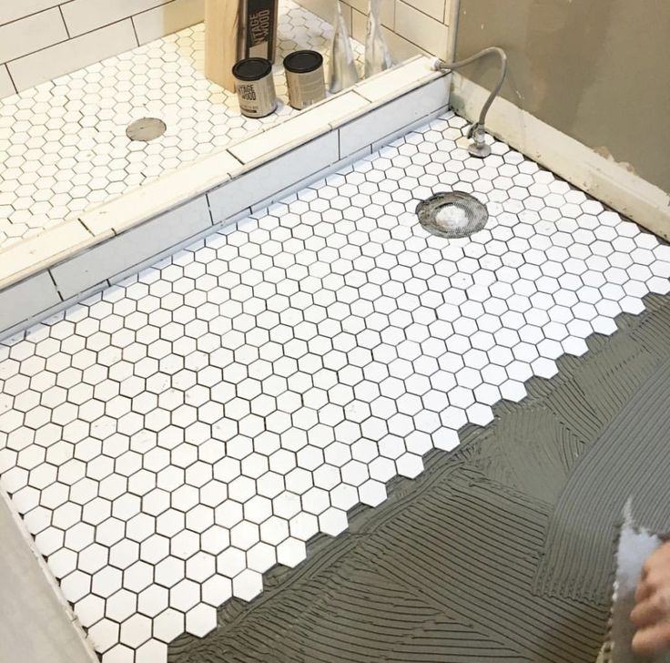 a bathroom with white hexagonal tiles on the floor, and a shower head