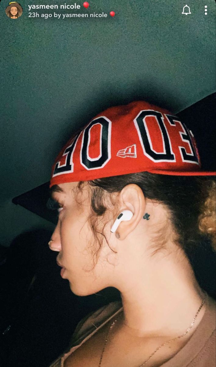 a girl with ear piercings wearing a red hat