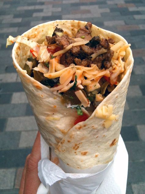 a burrito filled with meat, cheese and vegetables