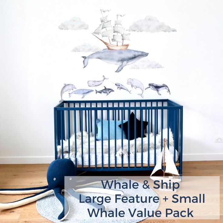 the whale and ship wall decal is next to a blue crib