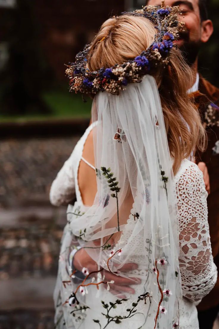 a man and woman standing next to each other in front of a building with flowers on their head