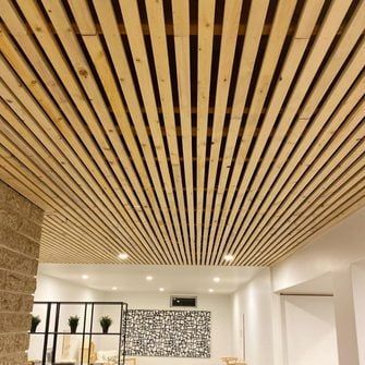 a living room filled with lots of furniture and wood slats on the ceiling above