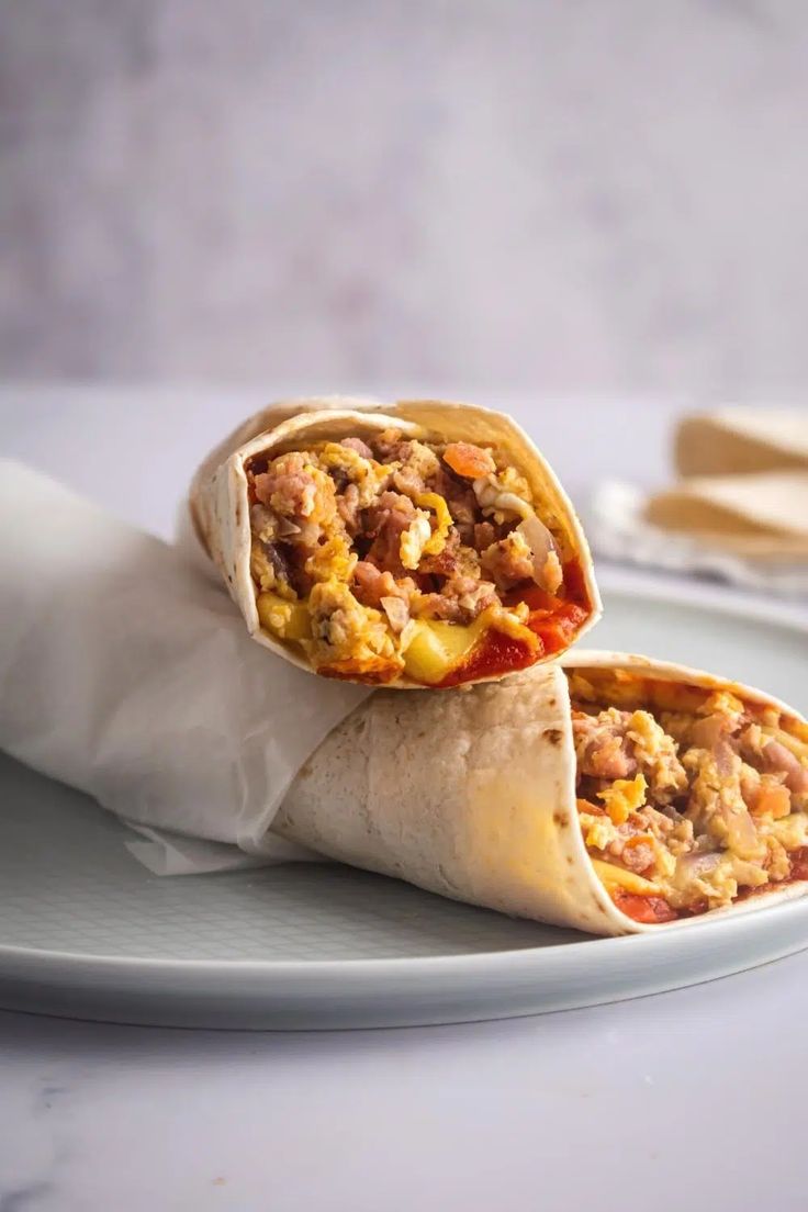 two burritos sitting on top of a white plate