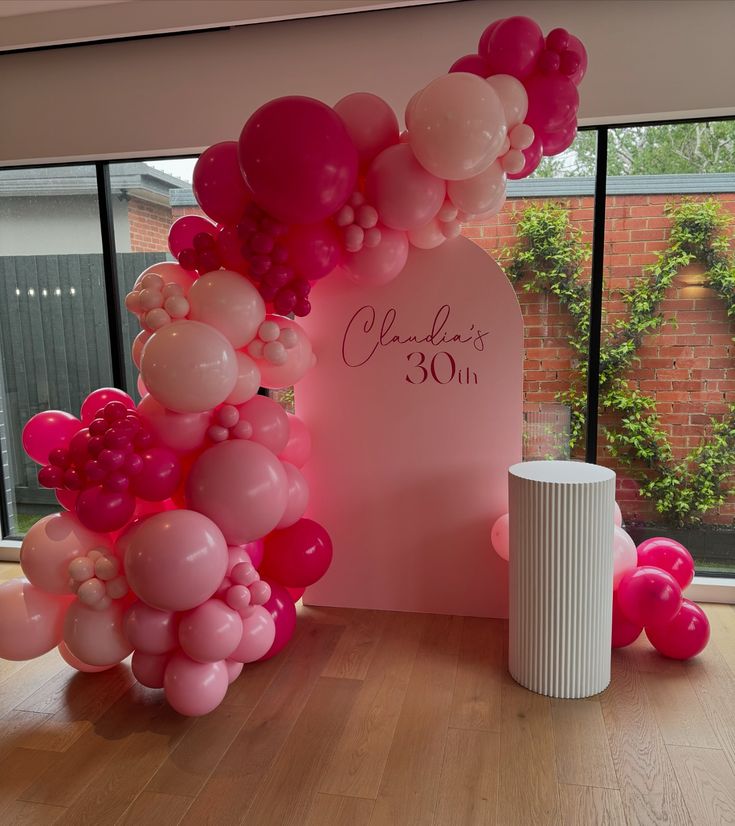 balloon arch with pink and white balloons in front of large window at entrance to building