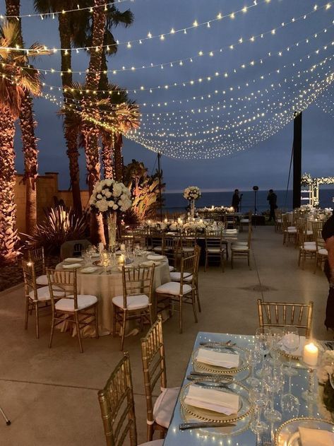 tables and chairs are set up for an event with string lights strung over the top