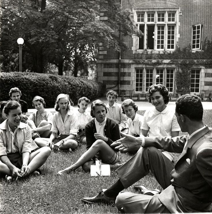 a group of people sitting on the grass in front of a building