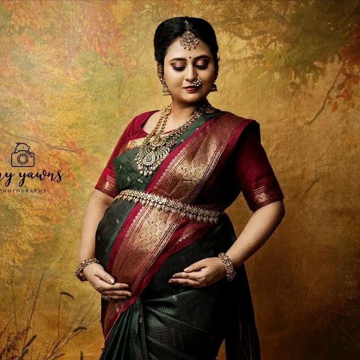 a woman in a green and red sari with her hands on her hips, posing for