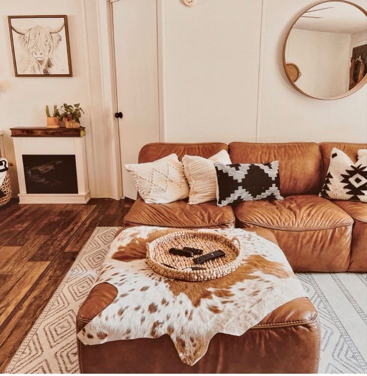 a living room with brown leather couches and cow hide rugs on the floor