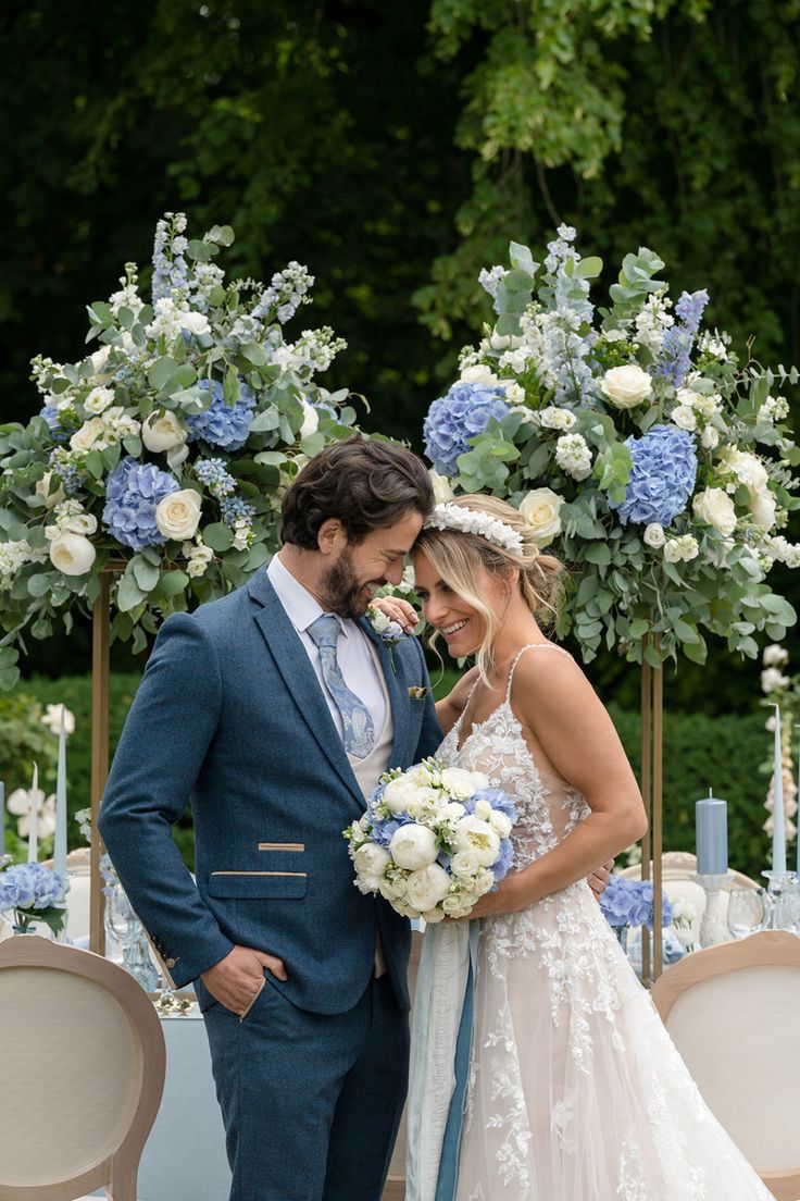 a bride and groom standing next to each other in front of an arch with flowers