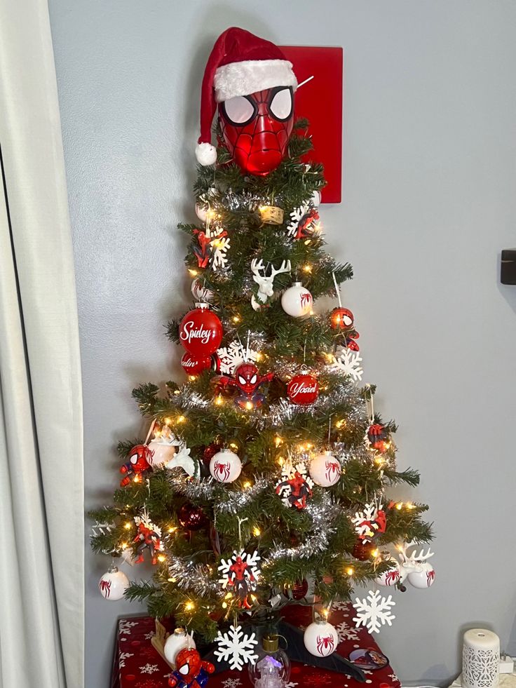 a decorated christmas tree in the corner of a room with a spiderman mask on it