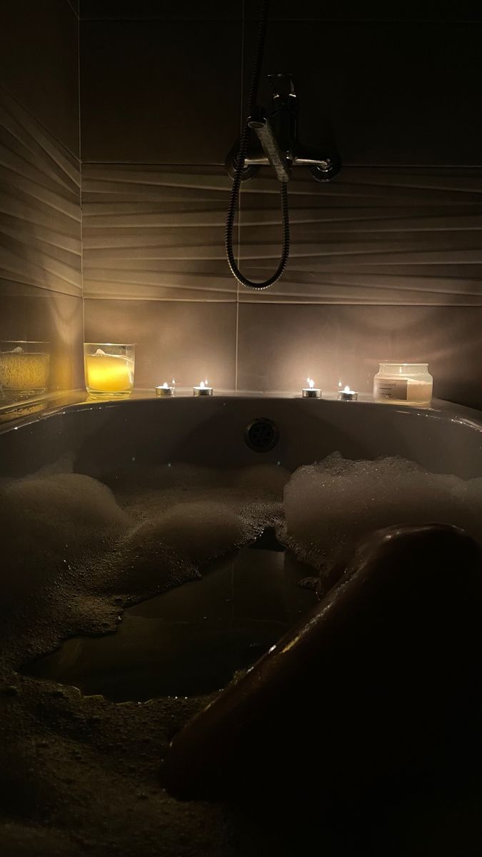 a bathtub filled with lots of foam next to candles