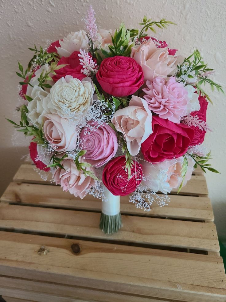 a bouquet of pink and white flowers sitting on top of a wooden crate