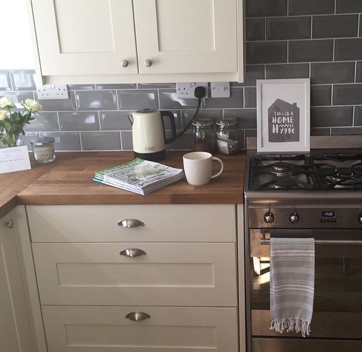 a kitchen with white cabinets and gray tile backsplashing, coffee pot on the stove