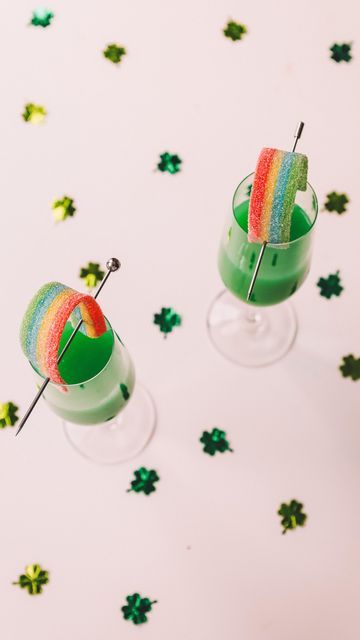 two glasses filled with green liquid and rainbow candy