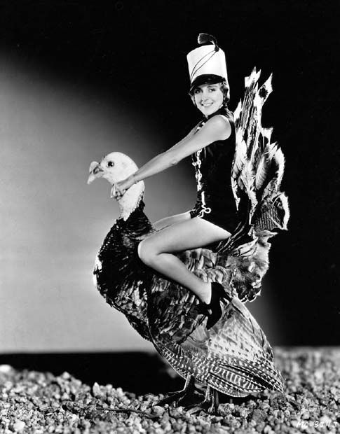 a black and white photo of a woman holding a bird