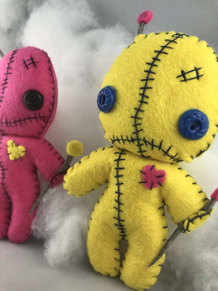 two voodoo dolls sitting next to each other on some white fluffy material with blue eyes