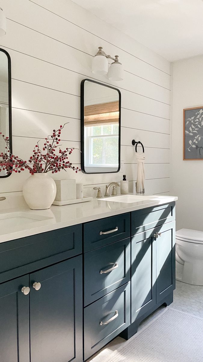 a bathroom with two sinks, a toilet and a large mirror on the wall above it