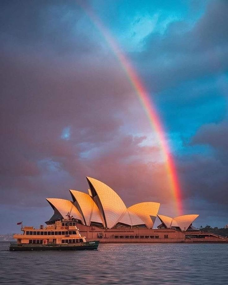 a rainbow over the sydney opera house with a boat under it and a double rainbow in the sky