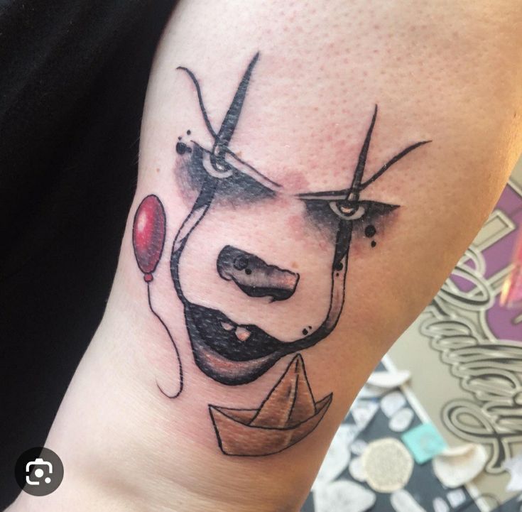 a tattoo on the arm of a person with scissors and a boat in front of it