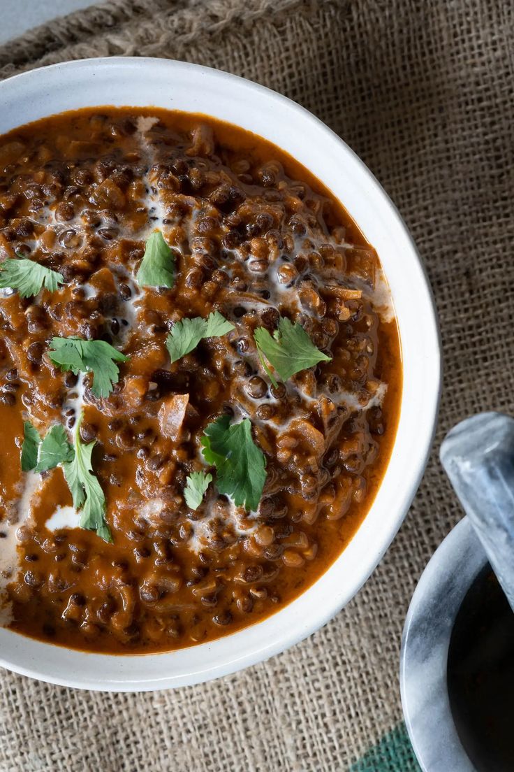 a white bowl filled with chili and beans on top of a burlied cloth