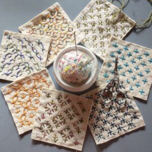 the table is covered with different types of handmade coasters and thread spools