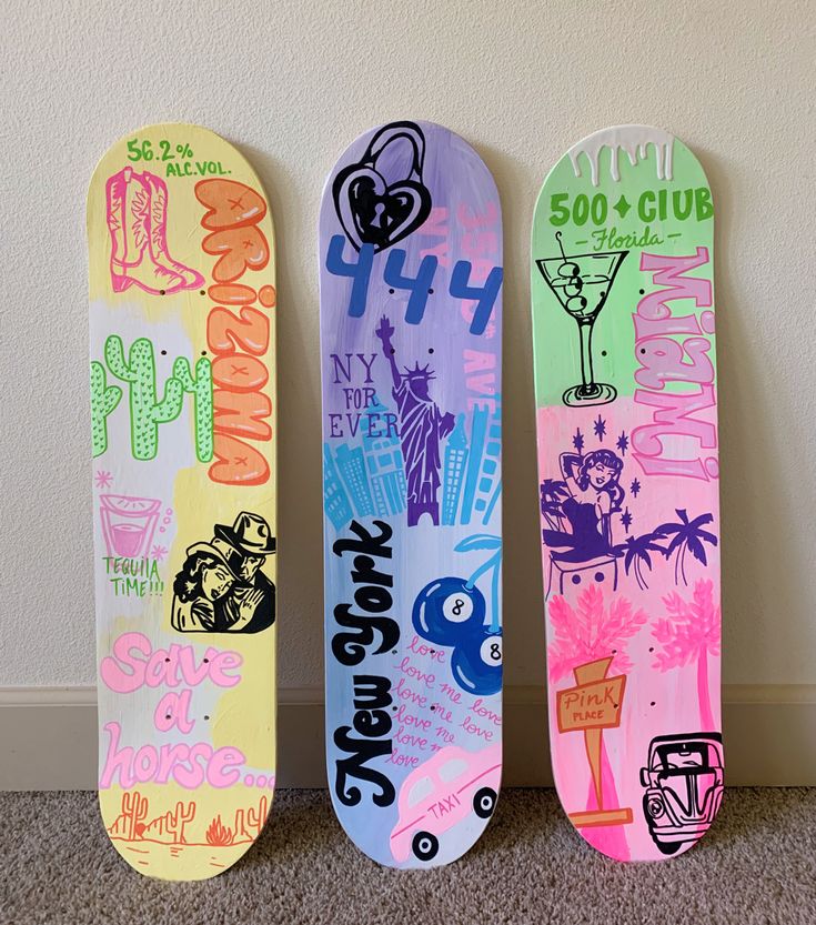 three skateboards are lined up against the wall with different designs and colors on them